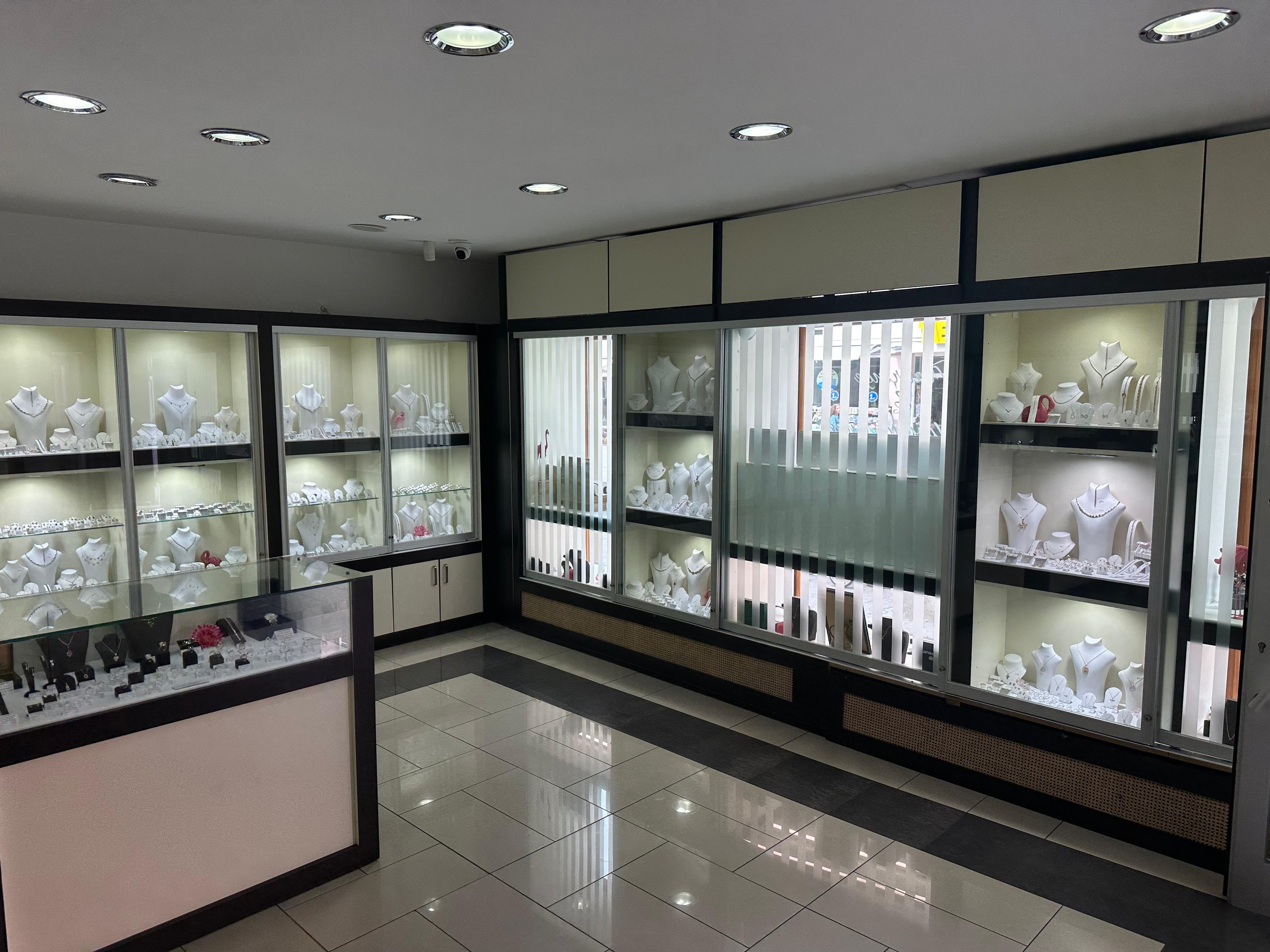 Beleuchtete Glasvitrinen in einem Juweliergeschäft zeigen eleganten Schmuck auf weißen Büsten und Displays.