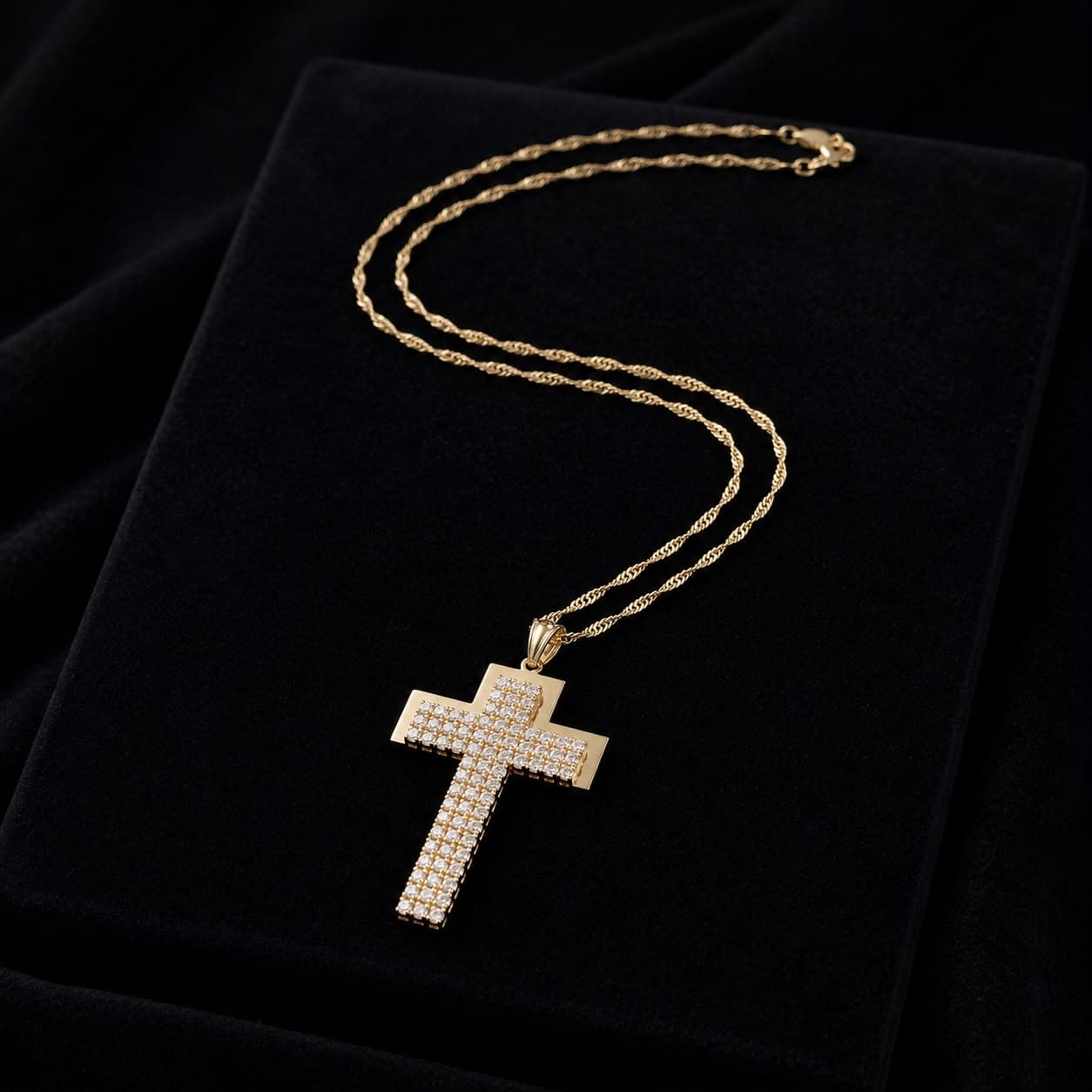Goldene Halskette mit einem großen, diamantbesetzten Kreuzanhänger auf schwarzem Samt präsentiert.