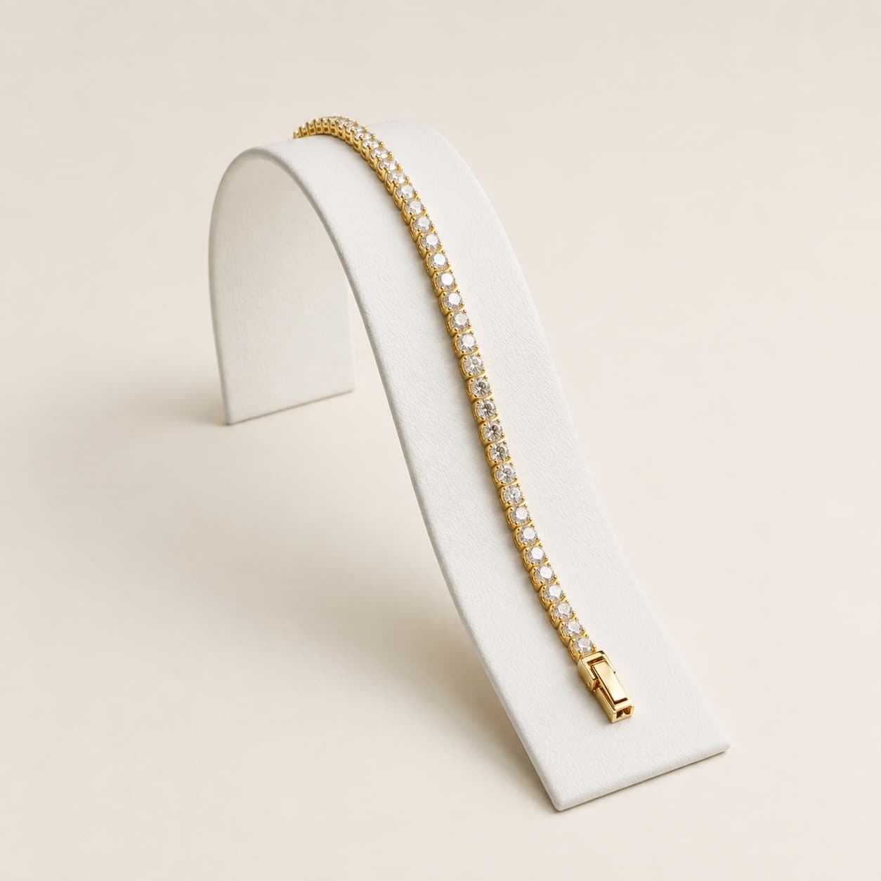 Goldenes Tennisarmband mit funkelnden Diamanten auf einem weißen, geschwungenen Schmuckständer vor neutralem Hintergrund.