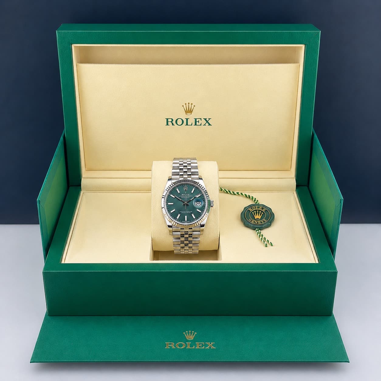 Rolex Datejust Armbanduhr mit grünem Zifferblatt in einer offenen grünen Box mit beigem Innenfutter.
